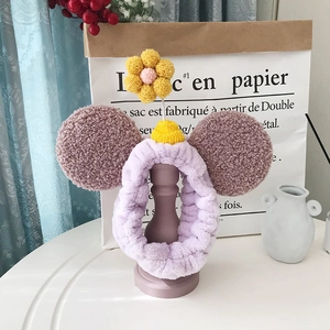 Gedetailleerde weergave van een paarse pluche hoofdband met bruine oren en 3D-gebreide bloem