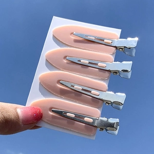 Set of four light pink seamless hair clips displayed on a card against a blue sky