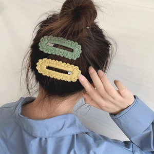 Handmade knitted wave edge BB hair clips in green and yellow colors worn by a model