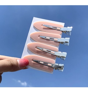 Set of four light pink acrylic creaseless hair clips on white card with blue sky background