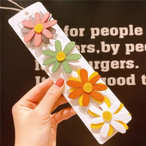 Set di quattro fermagli per capelli a forma di margherita colorata su carta espositiva