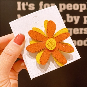 Dettaglio ravvicinato di fermaglio per capelli a girasole con petali in feltro giallo