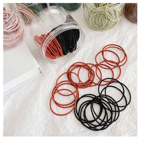 Détail d'élastiques à cheveux colorés haute élasticité dans un pot sur un tissu blanc doux