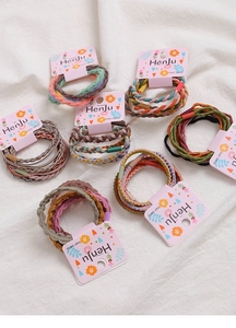 Close-up of assorted colorful braided hair ties sets on pink display cards