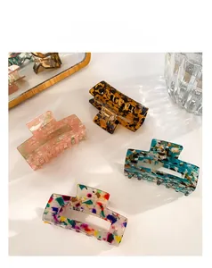 Macro detail of four acetate hair claws in floral, marble, and tortoiseshell patterns
