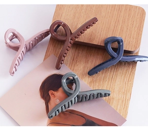Group of large cross-design hair claws in four Morandi colors on a natural wooden background