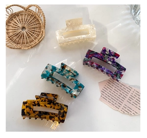 Detail view of four large acetate hair claws in floral and tortoiseshell patterns