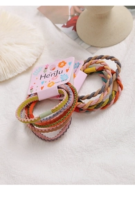 Macro detail of high-elasticity braided hair bands in Morandi colors on floral card