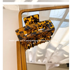 Macro view of leopard print acetate hair claw clip showing teeth details on a mirror
