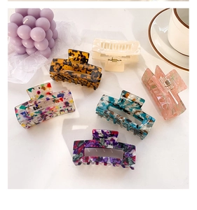 Detailed overhead view of six large acetate hair claws with marble and floral patterns