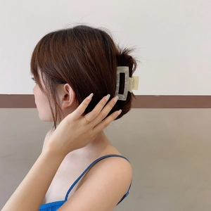 Large acetate hair claw clip with grey marble pattern on woman's elegant updo