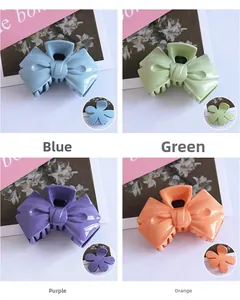 Detail of four candy-colored bow-shaped plastic hair claws in blue green purple and orange
