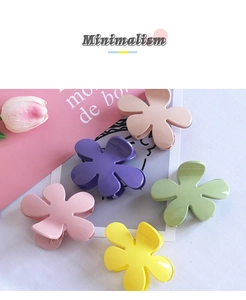 Detail view of glossy flower-shaped hair claws in assorted pastel candy colors