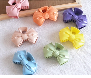 Set of 7 colorful ribbon-shaped hair claws in sweet candy colors on white fabric
