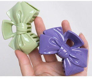 Close-up of candy-colored bow hair claws in light green and purple plastic