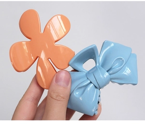 Close-up of bright orange flower and light blue bow plastic hair claws with glossy finish