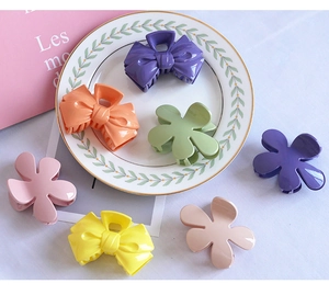 Close-up of candy-colored plastic flower and bow hair clips on a white ceramic plate