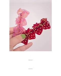 Détails des barrettes fraises en résine avec texture dorée et petits strass brillants