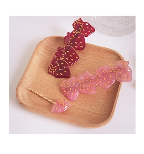 Détail d'un ensemble de barrettes fraises rouges et roses sur un plateau en bois