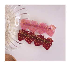 Vue détaillée des jolies barrettes fraises en résine avec texture dorée et petits diamants