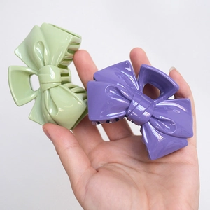 Pastel bow-shaped plastic hair claws in green and purple colors for women's hair styling