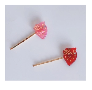 Détail de barrettes fraises rouges et roses avec paillettes dorées et petits strass