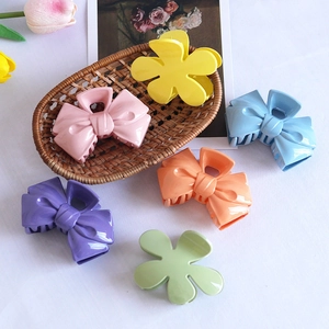 Candy-colored plastic hair claws with flower and bow designs in various pastel shades