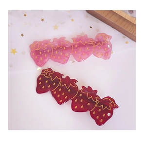Détails des barrettes fraise en acrylique rouge et rose avec des contours dorés