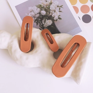 Set of three matte orange-brown hair clips in various sizes with minimalist oval design