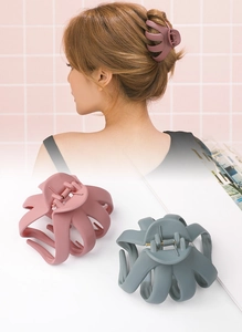 Detail view of large matte hair claws in dusty purple and green with octopus claw design