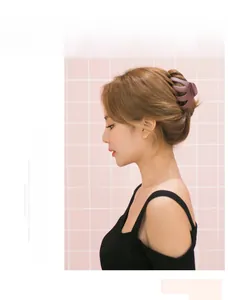Detail view of large matte dark purple hair claw clip used in a bun on pink background