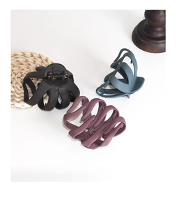 Detail of matte finish hair claws in black, grey blue and purple with a hollow curved design