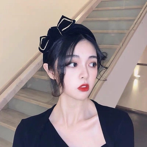 Detail of black velvet headband with gold-trimmed bows on a model in a warm setting