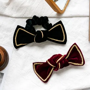Detailed close-up of velvet bow hair ties with gold trim and retro texture