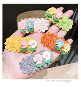 Detailed macro of five colorful hand-knitted floral hair clips with resin daisy accents