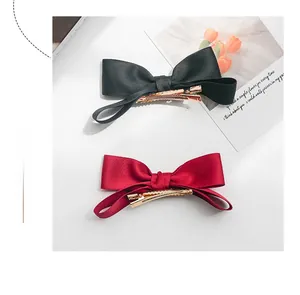 Close-up of black and burgundy satin bow hair clips with golden metal duckbill clips