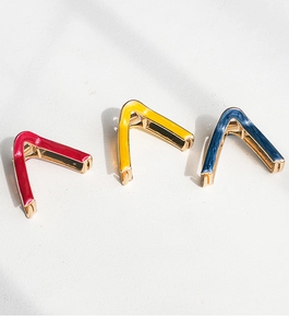 Detail of V-shaped metal hair claws in vibrant red, yellow, and blue enamel finish