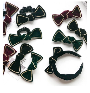 Macro shot of velvet bow hair clips and scrunchies with golden woven edge trim