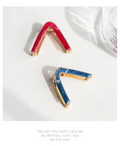 Detail view of V-shaped gold alloy hair clips with red and blue marble drip oil finish