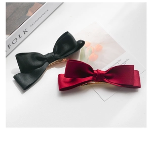 Detailed view of large black and wine red satin bow hair clips with gold metal duckbill clips