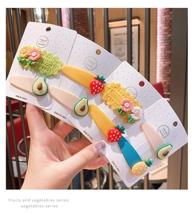 Detailed view of handmade crochet daisy and fruit hair clips on a white display card