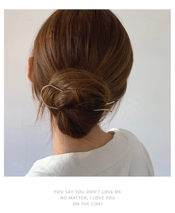 Detail view of a minimalist gold U-shaped metal hair pin styled in a sleek bun updo