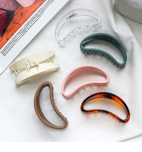Detailed set of six colorful moon-shaped hair clips on white fabric in a flat lay view