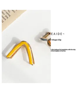 Detailed view of a yellow enamel V-shaped metal hair claw clip on a textured background