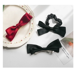 Close-up of silk satin bow hair clips and a black scrunchie in an elegant French setting