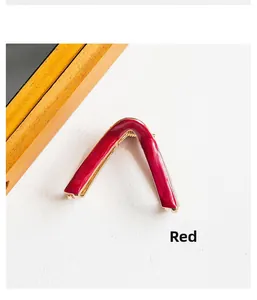 Close-up of elegant V-shaped hair claw clip in dark red enamel and gold metal finish