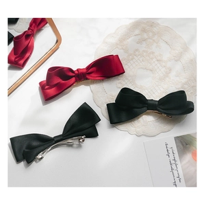 Detail view of large satin bow hair clips in black and wine red with elegant metal clips