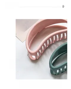 Detail view of glossy pink and dark green hair claw clips with smooth teeth on white