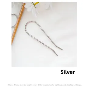 Close-up of minimalist silver U-shaped hair pin on a white fabric with daisy decor