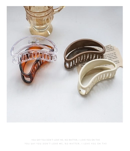 Minimalist resin hair claws in amber and cream tones on a decorative background